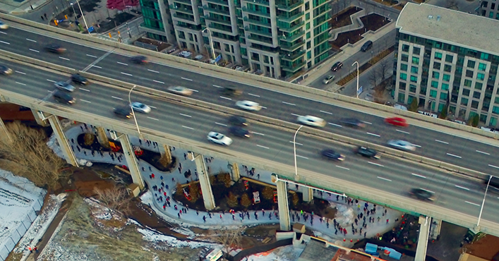 People skating on figure eight loop underneath elevated expressway. 